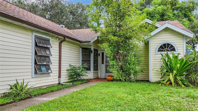 exterior space featuring roof with shingles and a yard