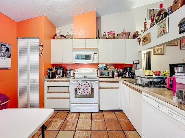 kitchen with white appliances, light countertops, a textured ceiling, and white cabinets