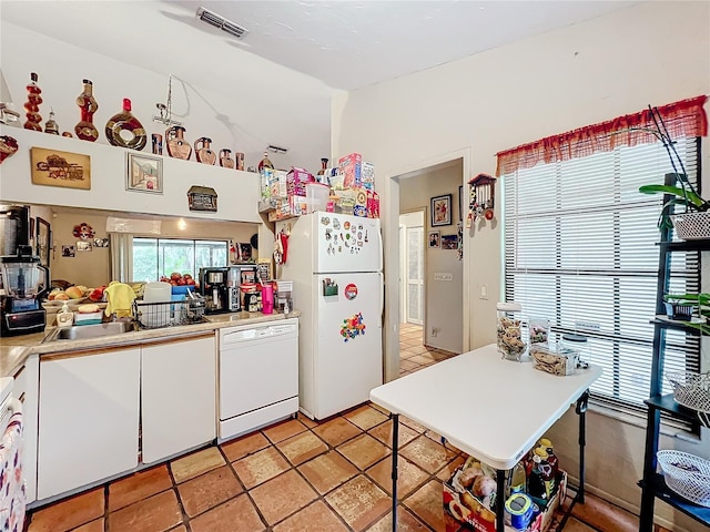 kitchen featuring white appliances, visible vents, white cabinets, light countertops, and a sink