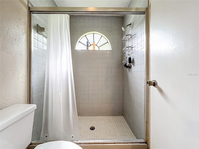 bathroom featuring toilet, a shower stall, and a textured wall