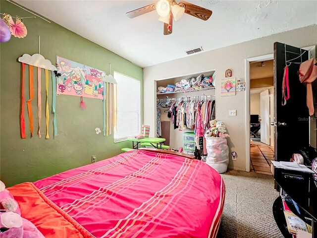 carpeted bedroom with a ceiling fan, a closet, and visible vents