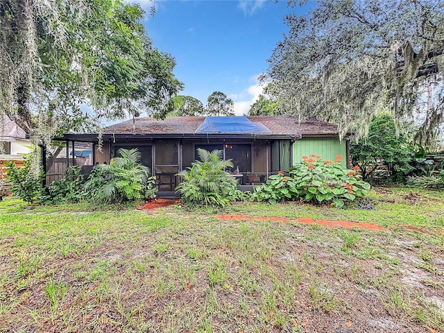 rear view of house featuring a sunroom and a yard