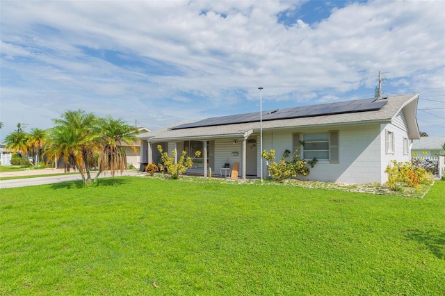 rear view of house with solar panels and a lawn