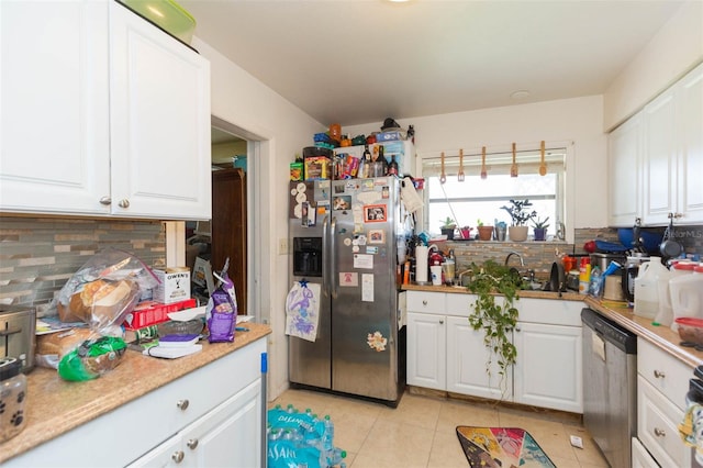 kitchen with light tile patterned flooring, appliances with stainless steel finishes, tasteful backsplash, and white cabinets