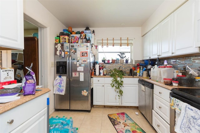 kitchen with light tile patterned floors, sink, appliances with stainless steel finishes, tasteful backsplash, and white cabinetry