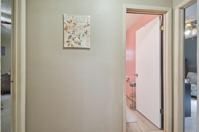 hall featuring light hardwood / wood-style floors and a textured ceiling