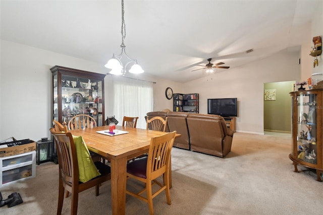 dining room with ceiling fan with notable chandelier, light colored carpet, and lofted ceiling