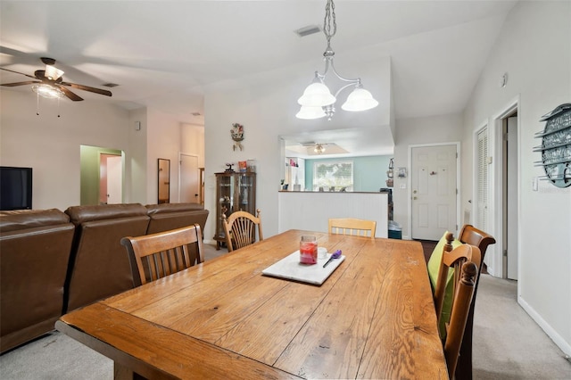 dining space with light carpet and ceiling fan with notable chandelier