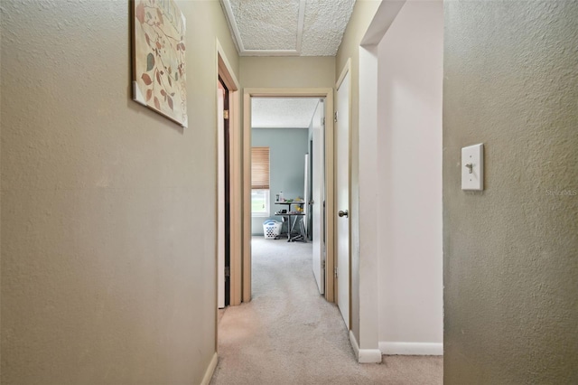 hallway featuring light carpet and a textured ceiling