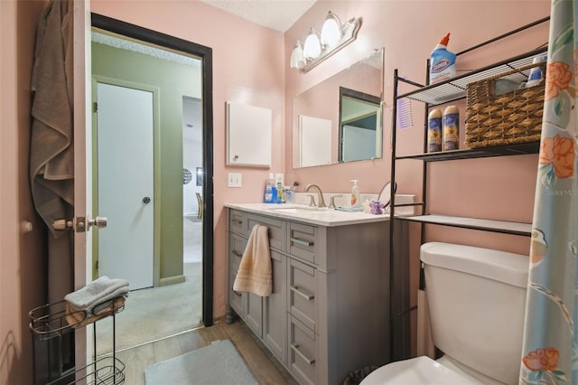 bathroom featuring vanity, wood-type flooring, a textured ceiling, and toilet