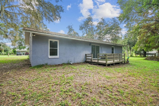 rear view of house with a lawn and a wooden deck