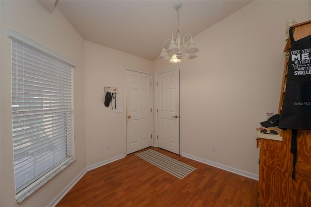 unfurnished dining area featuring a notable chandelier, lofted ceiling, and hardwood / wood-style floors