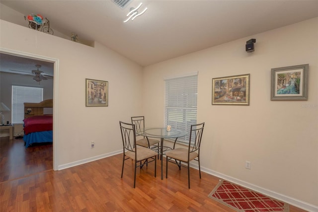 dining space with ceiling fan, hardwood / wood-style flooring, and lofted ceiling