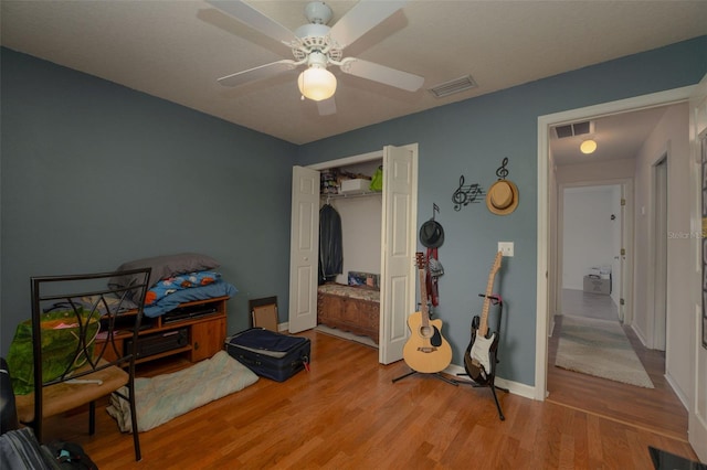 bedroom featuring light hardwood / wood-style flooring, ceiling fan, and a closet