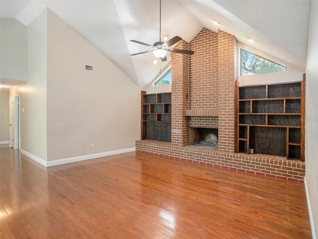 unfurnished living room featuring ceiling fan, a fireplace, hardwood / wood-style flooring, and brick wall