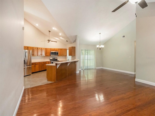 kitchen with light hardwood / wood-style floors, high vaulted ceiling, and stainless steel appliances