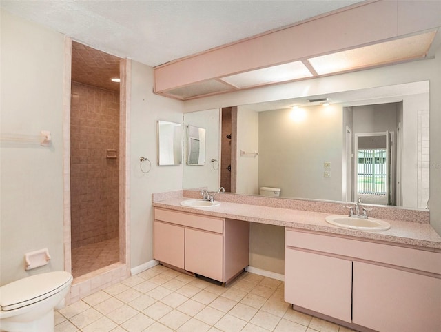 bathroom with tile patterned flooring, toilet, a tile shower, and vanity