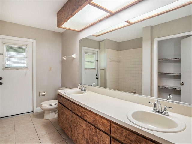 bathroom with tile patterned flooring, toilet, vanity, and tiled shower