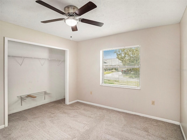 unfurnished bedroom featuring ceiling fan, a closet, light carpet, and a textured ceiling