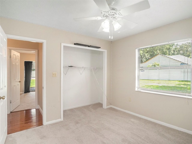 unfurnished bedroom featuring a closet, ceiling fan, multiple windows, and light colored carpet