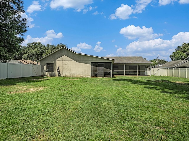 rear view of house with a sunroom and a yard