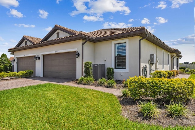 view of front of property featuring a garage, a front lawn, and cooling unit