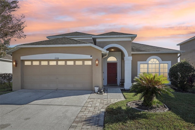 7720 Rathdown Ln, Wesley Chapel, FL 33545 - view of front facade featuring stucco siding, an attached garage, driveway, roof with shingles, and a yard