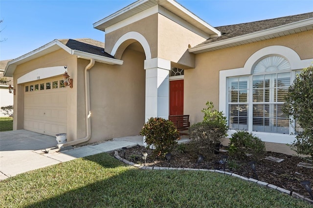 view of exterior entry with a garage and a yard