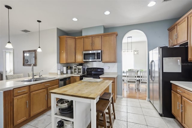 7720 Rathdown Ln, Wesley Chapel, FL 33545 - kitchen featuring appliances with stainless steel finishes, wooden counters, a peninsula, light tile patterned floors, and decorative light fixtures
