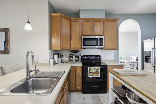 kitchen featuring sink, hanging light fixtures, backsplash, light tile patterned floors, and appliances with stainless steel finishes