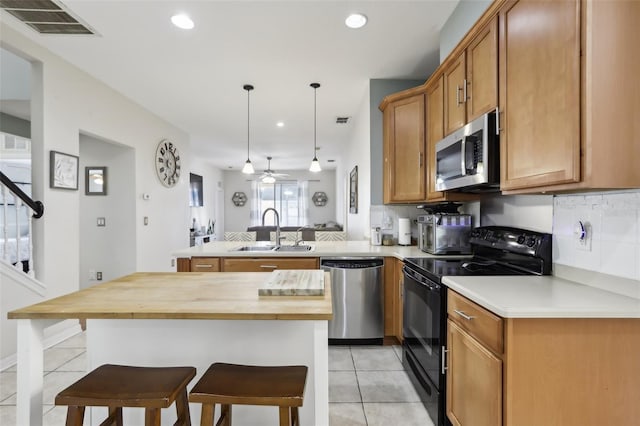 7720 Rathdown Ln, Wesley Chapel, FL 33545 - kitchen with appliances with stainless steel finishes, wooden counters, light tile patterned floors, a peninsula, and a breakfast bar area