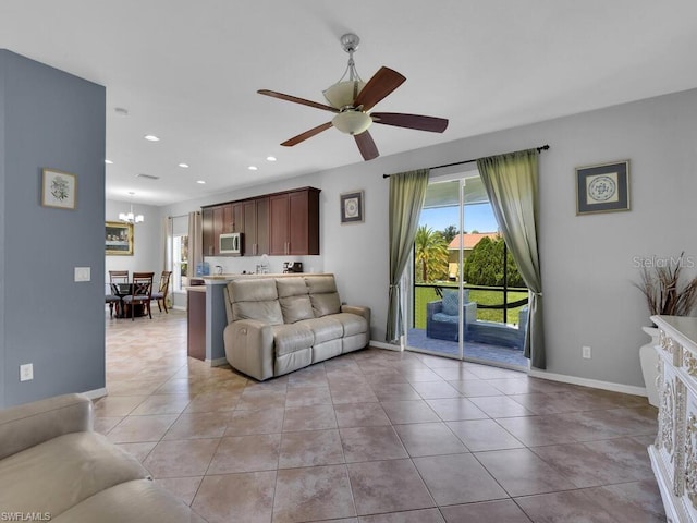 living room with ceiling fan with notable chandelier and light tile patterned floors