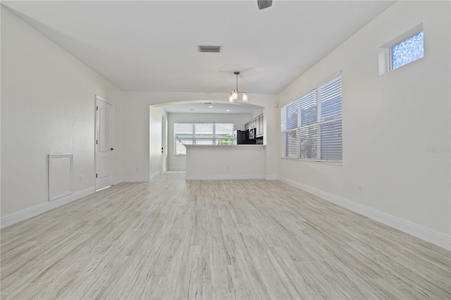 unfurnished living room featuring an inviting chandelier and light wood-type flooring