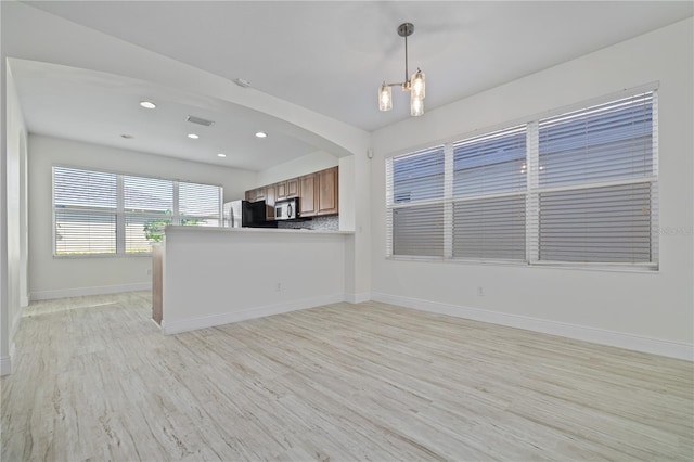 unfurnished living room featuring a notable chandelier and light wood-type flooring