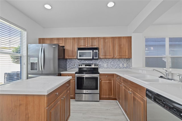 kitchen with stainless steel appliances, sink, tasteful backsplash, and light hardwood / wood-style flooring