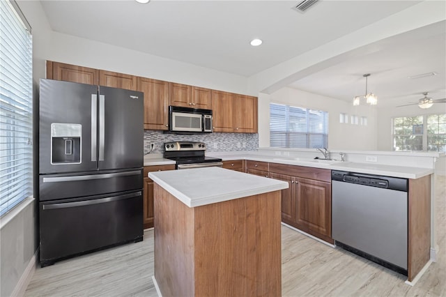 kitchen featuring appliances with stainless steel finishes, ceiling fan with notable chandelier, a kitchen island, and plenty of natural light