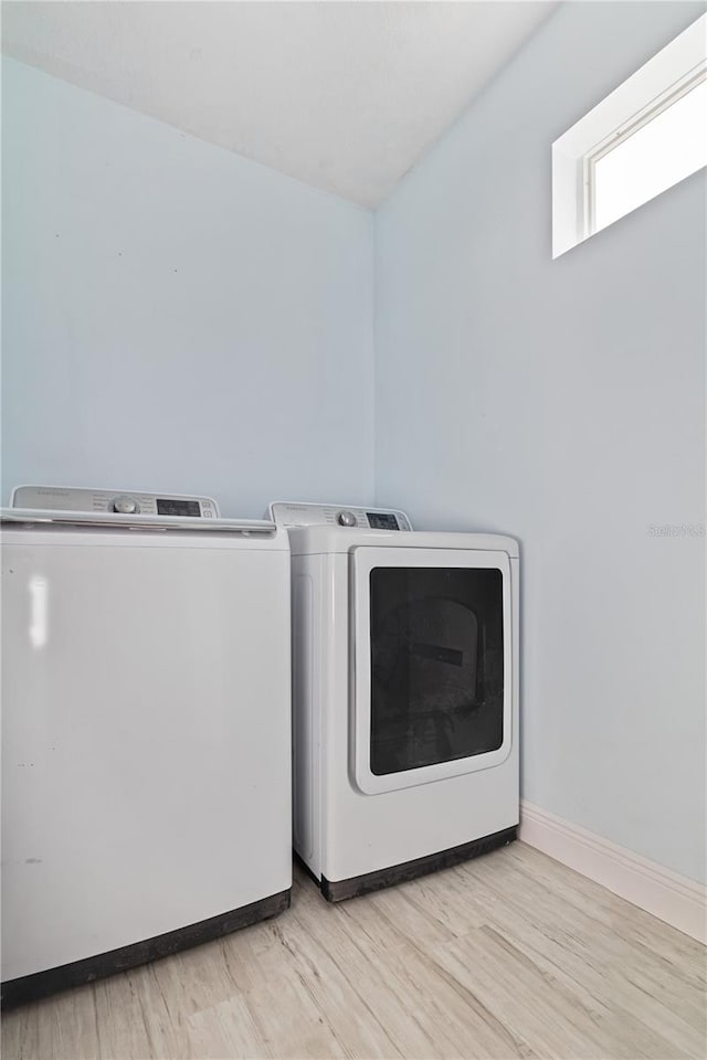 laundry area with washer and clothes dryer and light wood-type flooring