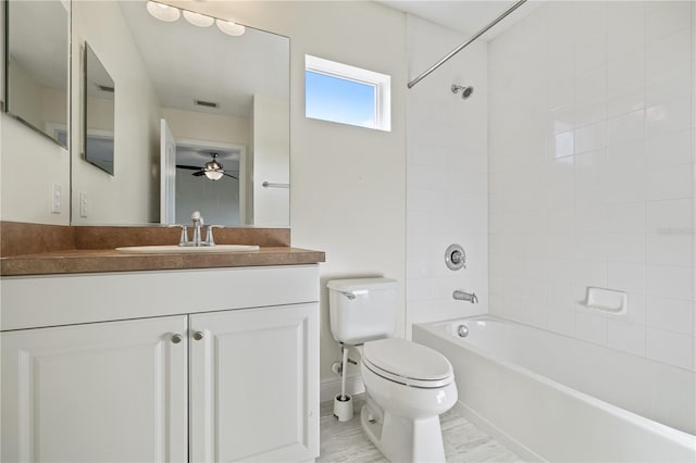 full bathroom with ceiling fan, tiled shower / bath, vanity, and toilet