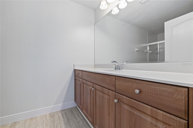 bathroom featuring wood-type flooring, a shower with door, and vanity