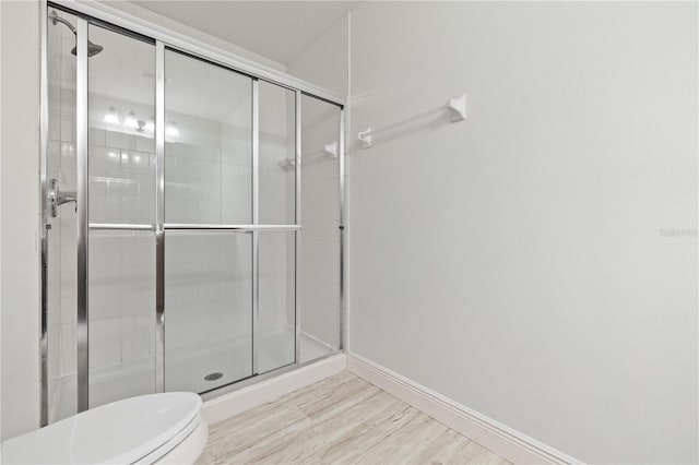 bathroom with hardwood / wood-style floors, toilet, and a shower with shower door