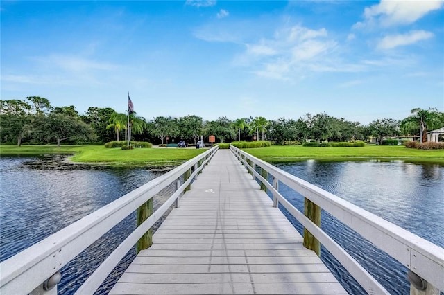 view of dock featuring a lawn and a water view