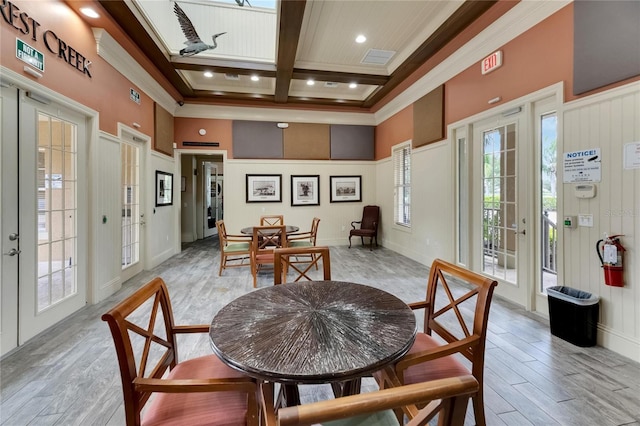 dining space with french doors, light hardwood / wood-style floors, ornamental molding, and coffered ceiling