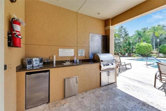 view of patio / terrace featuring exterior kitchen, area for grilling, a community pool, and sink