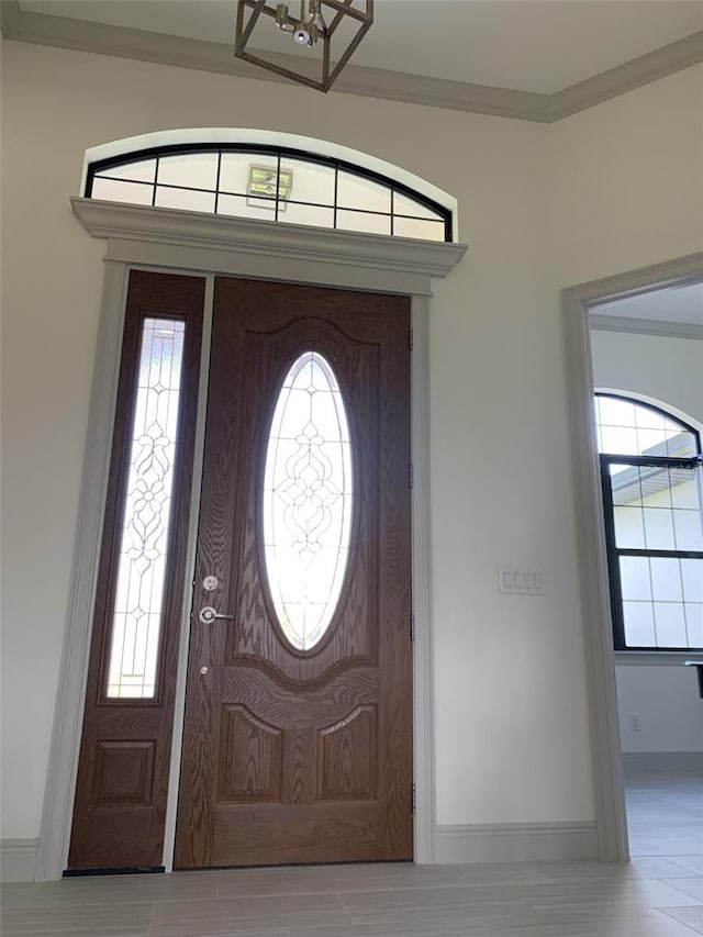 entrance foyer with crown molding and an inviting chandelier