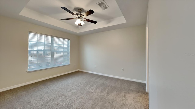 carpeted empty room with a tray ceiling and ceiling fan