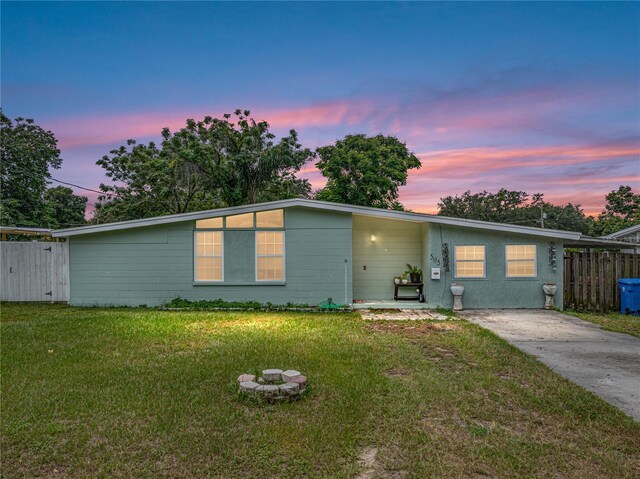 ranch-style home with an outdoor fire pit and a yard