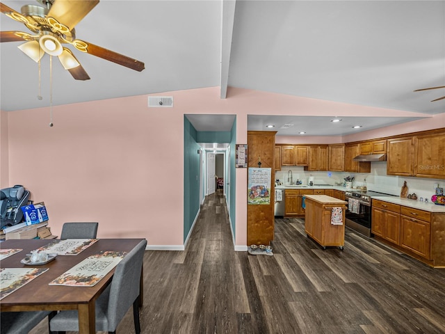 kitchen featuring ceiling fan, vaulted ceiling with beams, dark hardwood / wood-style flooring, a center island, and stainless steel appliances