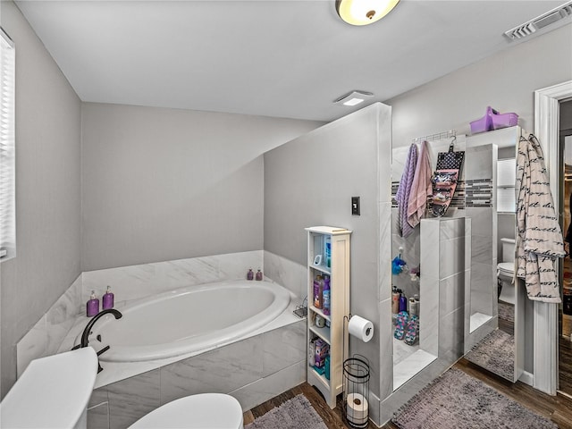 bathroom featuring hardwood / wood-style flooring, shower with separate bathtub, and toilet