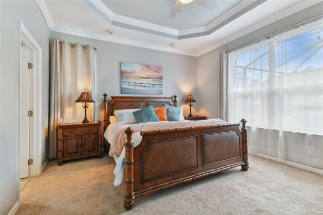 carpeted bedroom featuring ceiling fan, a raised ceiling, and crown molding