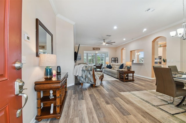 living area featuring baseboards, wood finished floors, and crown molding